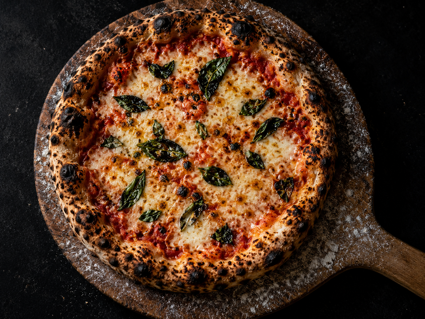 Whole round cheese pizza with charred crust on a wooden peel